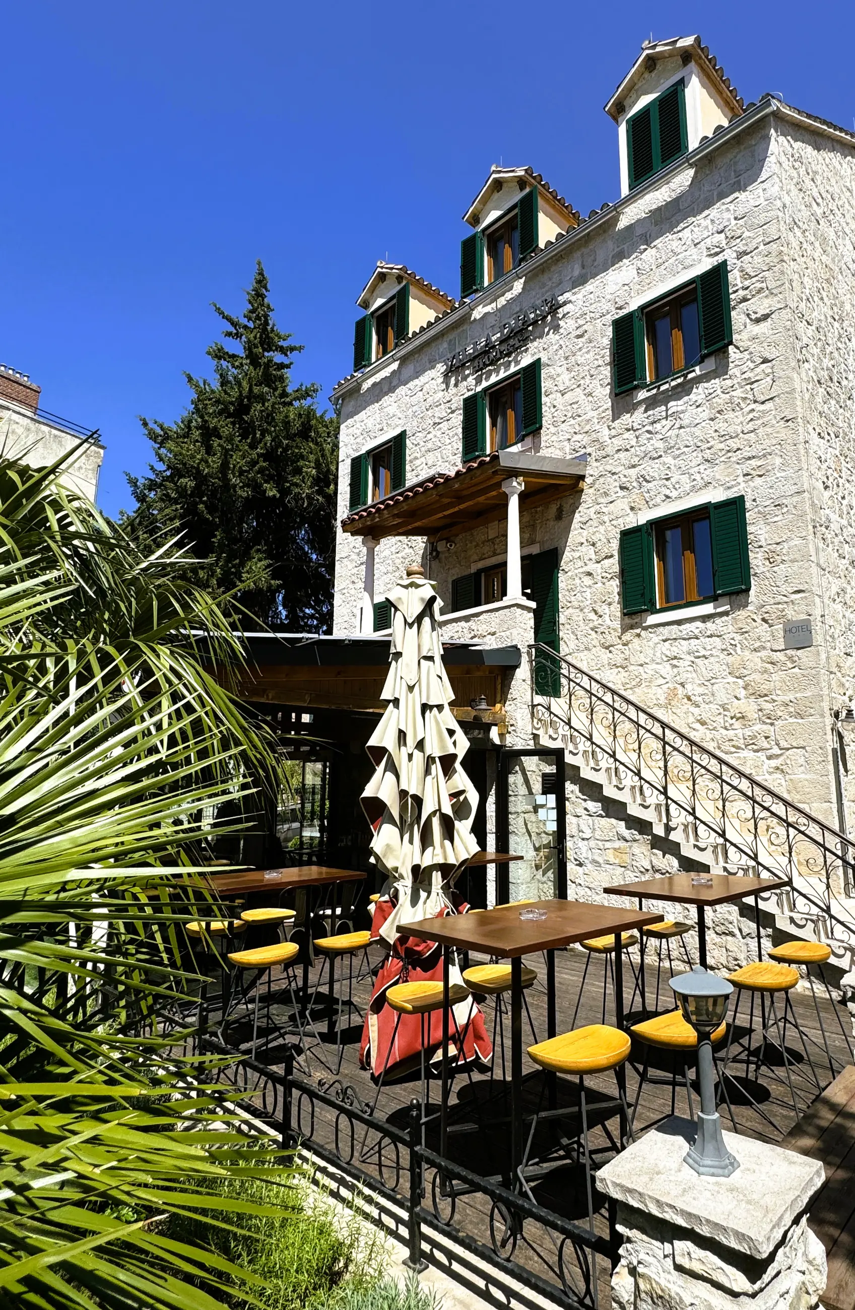 Terasa sa stolovima i suncobranom pod kamenim pročeljem, danju, Pizzeria Villa Diana, Lučac, Split