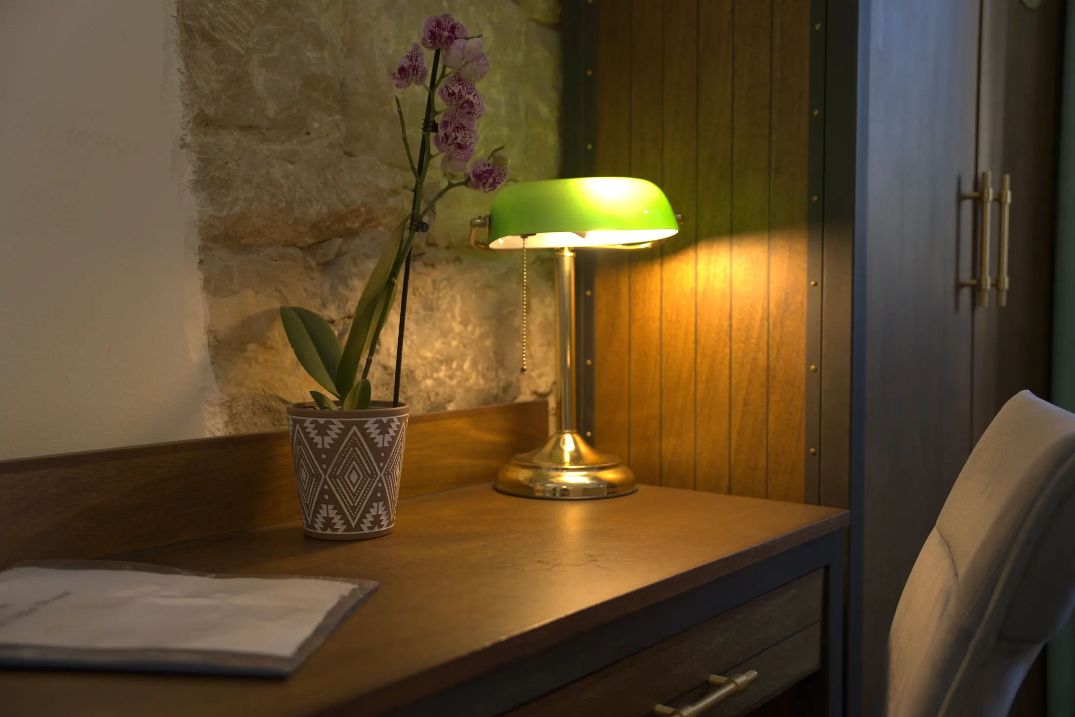 The desk with a green lamp and an orchid, beside the exposed stone wall, Hotel Villa Diana, Lučac, Split