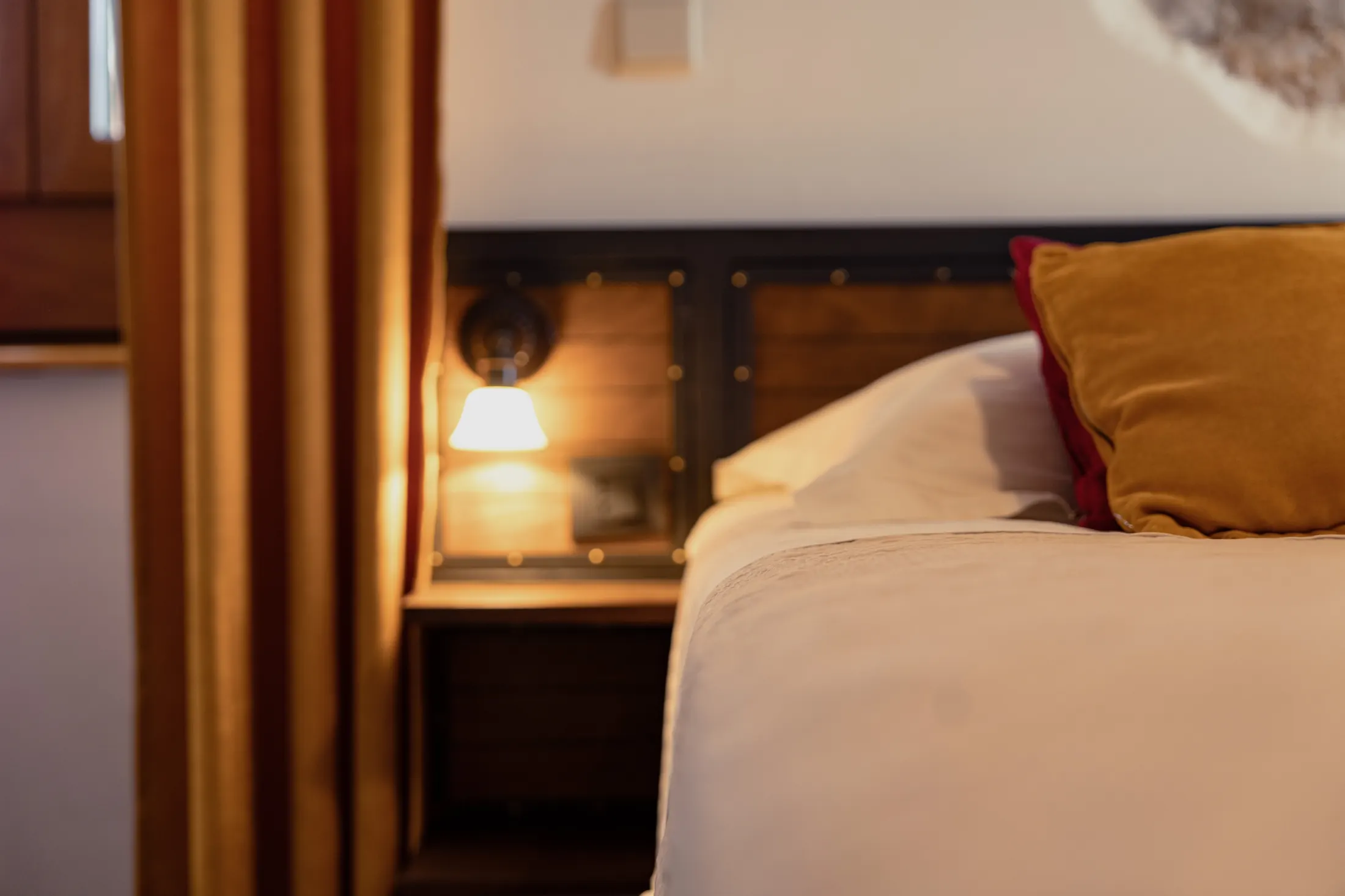 A reading lamp set into the headboard, beside the ochre curtain and window, Hotel Villa Diana, Lučac, Split